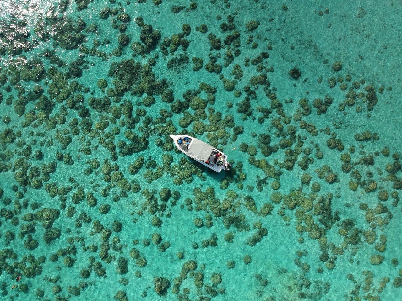 Stunning aerial shot of a boat navigating over the vibrant coral reef waters of Mauritius.